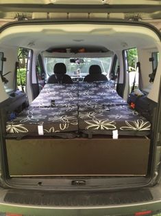 the back end of a van with two beds in it's cargo area,