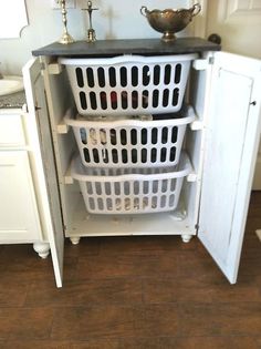 three laundry baskets stacked on top of each other in front of an open refrigerator door