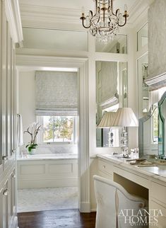 a white bathroom with a chandelier and vanity