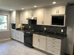 an empty kitchen with white cabinets and black counter tops is seen in this image from the front door