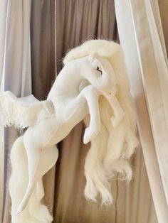 a white stuffed animal hanging from a curtain