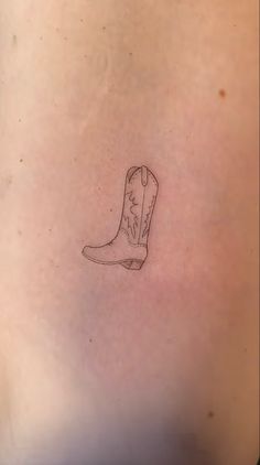 a small tattoo of a cowboy boot on the back of a woman's stomach