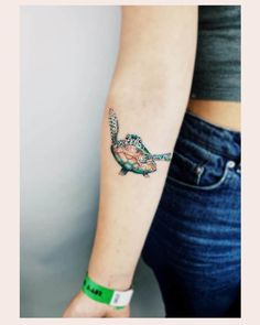 a woman's arm with a small turtle tattoo on it