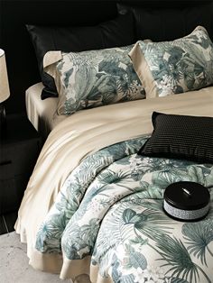 a bedroom with a bed covered in tropical print sheets and pillows, along with a black headboard