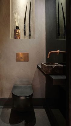 a black toilet sitting in a bathroom next to a sink and mirror on the wall