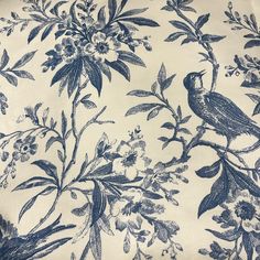 a blue and white floral print fabric with birds sitting on the branches in front of flowers