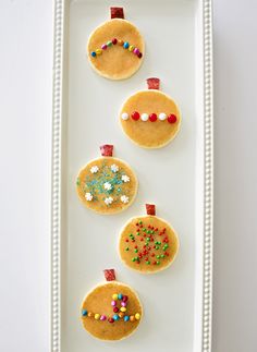 three christmas ornaments made out of pancakes on a white plate with sprinkles