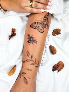 a woman's arm with butterflies on it and leaves around the wrist, while she is laying down