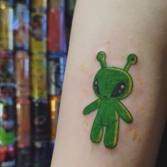 a small green alien tattoo on the arm