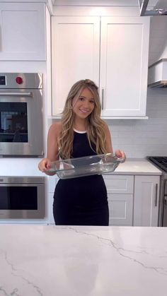 a woman in a black dress is holding a tray