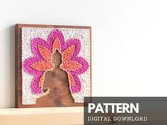 a crocheted flower is hanging on the wall next to a wooden shelf with a sign that says pattern