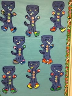 a bulletin board decorated with black cats on blue paper and flowers in the middle, surrounded by other magnets