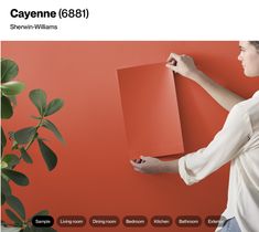 a woman holding a piece of paper in front of a red wall with the words cayenne 86 on it