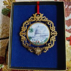 an ornament with the capitol building on it is in a blue velvet box