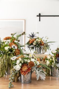 flowers are arranged in buckets on the table