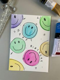 a card with smiley faces on it next to some paint