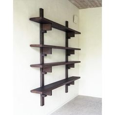 a wall mounted shelf in the corner of a room with white walls and concrete flooring