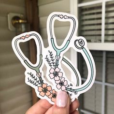 a hand holding up a sticker with flowers and stethoscopes on it