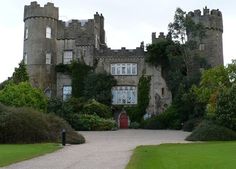 an old castle with a red door and green grass around it's entrance way