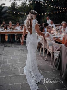 the back of a woman's wedding dress, with people sitting at tables in the background