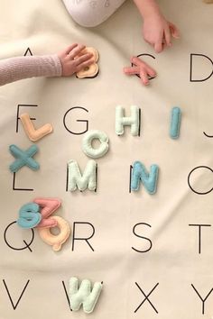 two children playing with letters and numbers on a sheet that is laid out in the shape of letters