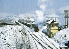 a train traveling down tracks next to snow covered hills