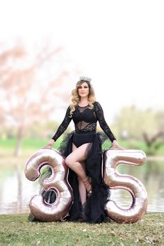 a woman in a black dress sitting on top of a number 35 balloon