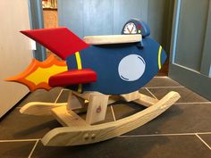 a wooden toy airplane sitting on top of a tile floor next to a door way