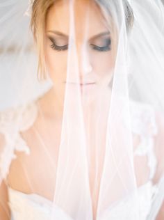 a woman wearing a veil and holding a flower in her hand while looking at the camera