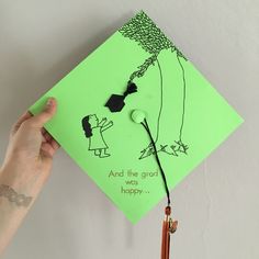 a hand holding a green graduation cap that says and the great is happy