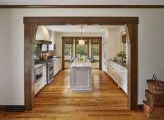 an open kitchen with wooden floors and white cabinets, along with a large center island