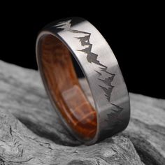 a wedding ring with an arrow design on it sitting on top of a tree stump