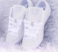 a pair of white sneakers with bows and pearls on the side, sitting on fluffy fur