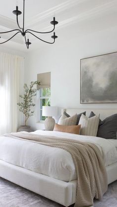 a bedroom with a large bed and a chandelier hanging from the ceiling above it