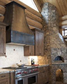 a stove top oven sitting inside of a kitchen next to a stone wall and ceiling