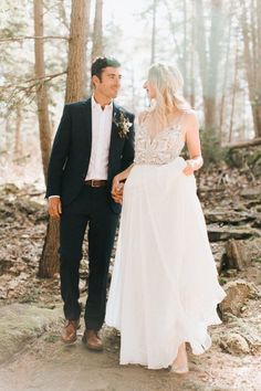 a bride and groom holding hands in the woods