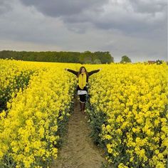 a woman standing in the middle of a yellow field