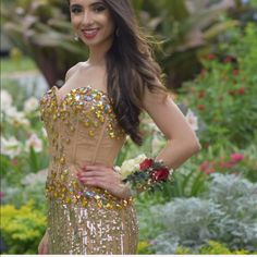 a beautiful woman in a gold dress posing for the camera with her hands on her hips