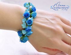 a woman's hand wearing a bracelet with blue flowers