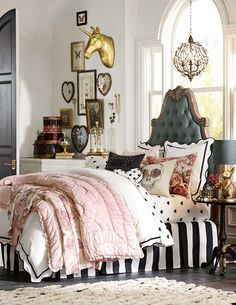 a bedroom with black and white striped bedding, pink comforter, and lots of pictures on the wall