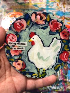 a person holding up a paper plate with flowers on it and a chicken in the center