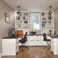 a home office with white cabinets and black chairs