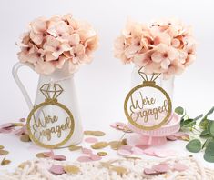 two vases with flowers in them sitting on a table next to confetti