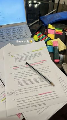 a laptop computer sitting on top of a desk next to papers and pens in front of it