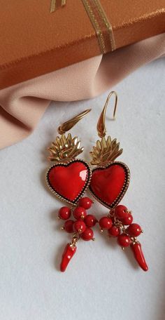 Religious earrings made of: - Enamelled Brass Sacred Heart (40 mm x 23 mm); - Smooth stones (6 mm), red color; - Brass italian horns; - Brass open hooks. Lenght : 8,5 cm / 3,35 inches * SHIPPING * Your order will be shipped within 1-3 business days from your purchase. You can choose between 2 shipping methods: STANDARD MAIL (NOT TRACEABLE) It is a cheap and fast shipping method, but NOT TRACEABLE. Chapeau Atelier is not responsible for any postal disruptions, delays or losses. REGISTERED MAIL (T Red Heart Charm Metal Earrings, Red Drop Earrings For Valentine's Day, Red Nickel-free Dangle Heart Earrings, Handmade Red Heart-shaped Jewelry, Nickel Free Red Jewelry For Valentine's Day, Nickel-free Red Jewelry For Valentine's Day, Red Nickel-free Jewelry For Valentine's Day, Red Metal Jewelry With Heart Charm, Red Dangle Earrings With Heart Beads