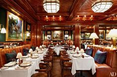 a dining room with wooden walls and tables covered in white tablecloths, brown leather seats