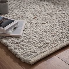 a cell phone sitting on top of a white rug next to a cup and coffee mug