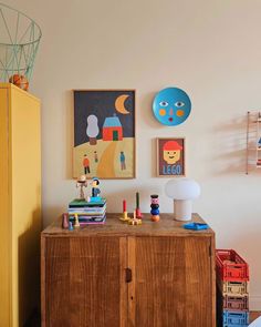 a wooden cabinet sitting next to a wall with pictures on it