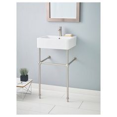 a bathroom sink sitting under a mirror next to a white tiled floor with a plant on it