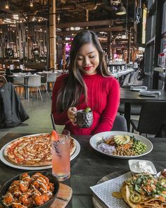 a woman sitting at a table with plates of food